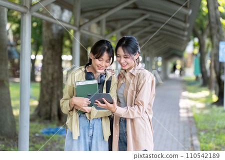 university students using a digital tablet while walking to next class university students using a digital tablet while walking to next class 110542189