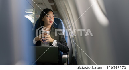 businesswoman flying and working in an airplane in first class, sitting inside an airplane using laptop 110542370