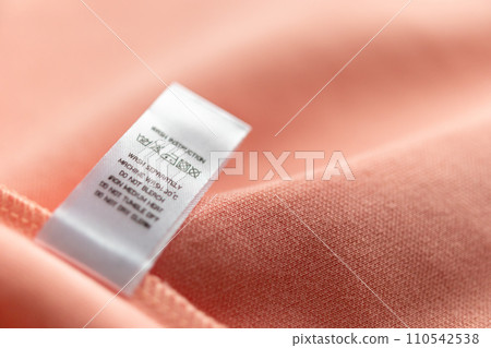 White laundry care washing instructions clothes label on pink cotton shirt White laundry care washing instructions clothes label on pink cotton shirt 110542538