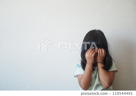 a upset child girl cover her face with hand  110544491