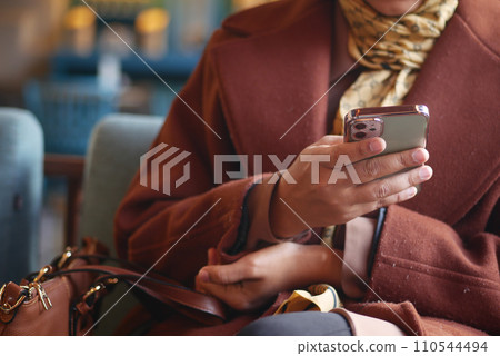 young women hand holding smart phone sitting on cafe sofa young women hand holding smart phone sitting on cafe sofa 110544494