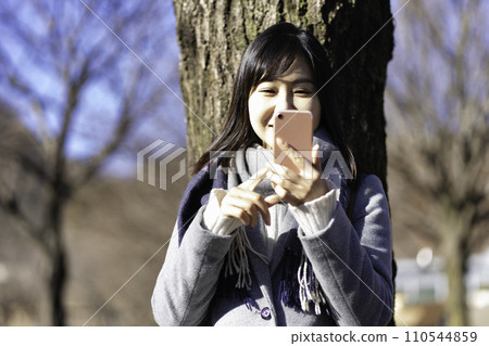 一名婦女在冬季公園使用智慧型手機 110544859