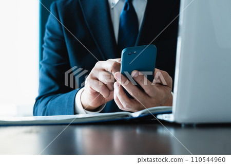 Hand of a businessman sending an email with a smartphone Hand of a businessman sending an email with a smartphone 110544960