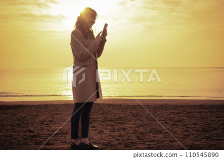 日落時分，一名婦女在冬海使用智慧型手機 110545890