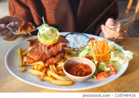 women eating Chicken schnitzel served with potato chips  110546416