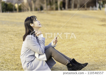 在冬季公園用智慧型手機聽音樂的女性 110546557