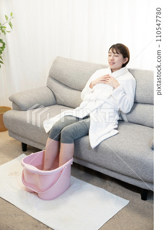 一個女人坐在沙發上使用足浴 一個女人坐在沙發上使用足浴 110547780
