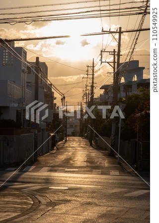 Straight street in the city at sunset with the sun in front 110549925