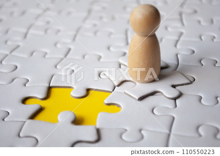 Wooden doll on top of jigsaw with missing jigsaw puzzle. Hiring and employment concept 110550223