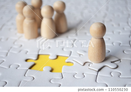 Wooden doll on top of jigsaw with missing jigsaw puzzle. Hiring and employment concept Wooden doll on top of jigsaw with missing jigsaw puzzle. Hiring and employment concept 110550230