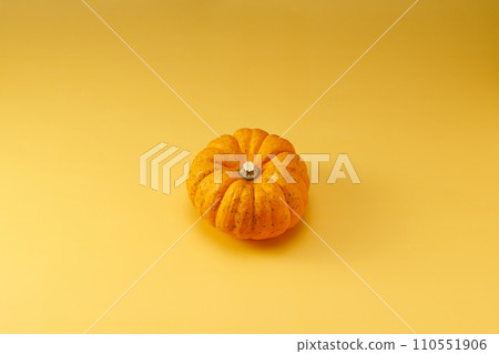 Overhead shot with a yellow background with one small pumpkin in the center Overhead shot with a yellow background with one small pumpkin in the center 110551906