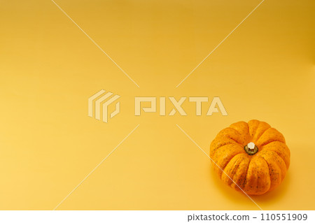 Overhead shot with a yellow background and one small pumpkin placed in the bottom right Overhead shot with a yellow background and one small pumpkin placed in the bottom right 110551909