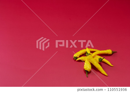 Overhead shot with multiple yellow chili peppers placed in the lower right with a red background Overhead shot with multiple yellow chili peppers placed in the lower right with a red background 110551936