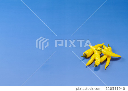 藍色背景的頭頂拍攝，左下角放置多個黃色辣椒 110551940
