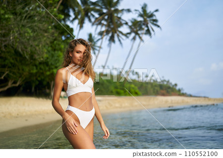 Fit solo female traveler enjoys tropical beach, slim woman in bikini explores paradise island coastline alone, healthy lifestyle. Fit solo female traveler enjoys tropical beach, slim woman in bikini explores paradise island coastline alone, healthy lifestyle. 110552100