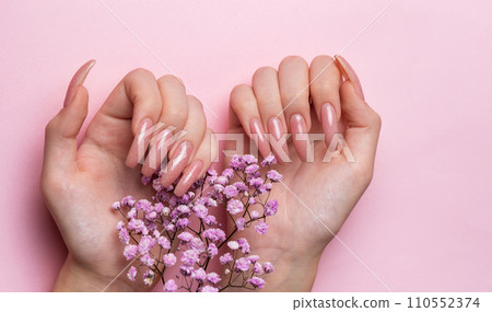 Female hands with pink nail design  hold gypsophila flowers. 110552374