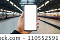 Mock up of a smartphone in the hand of a man at the train station. Generative AI. 110552591