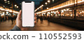 Mock up of a smartphone in the hand of a man at the train station. Generative AI. 110552593