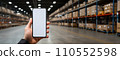 Smartphone mockup in male hand. Mobile phone with blank screen warehouse background. Advertisement application design or mock-up text. Storage app distribution business concept. Generative AI. 110552598
