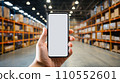 Smartphone mockup in male hand. Mobile phone with blank screen warehouse background. Advertisement application design or mock-up text. Storage app distribution business concept. Generative AI.  110552601