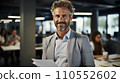 smiling entrepreneur in his 50s stands confidently in his well-appointed office, holding a stack of papers. Generative AI. Fictional person.  110552602