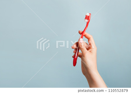 Woman holding red toothbrush against color blue background, copy space 110552879