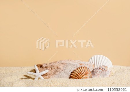 Seashells with starfish and stone on sand, beige background. Podium for cosmetics products. Sea summer vacation card with space for the text Seashells with starfish and stone on sand, beige background. Podium for cosmetics products. Sea summer vacation card with space for the text 110552961