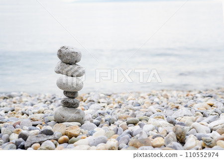 Pyramid of pebbles on the sea beach.Waves in background Pyramid of pebbles on the sea beach.Waves in background 110552974