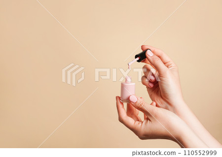 Light pink nail polish in females hands on beige background, copy space 110552999