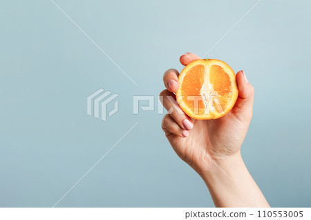 Female hand holding orange on blue background, copy space Female hand holding orange on blue background, copy space 110553005