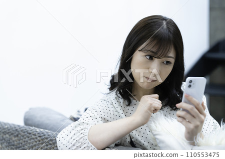 Middle-aged woman using a smartphone on the sofa in the living room 110553475