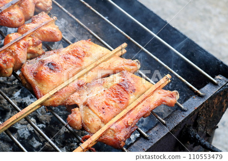 Thigh and leg of chicken grilling on stove and smoke. 110553479