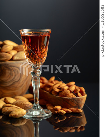 Italian liqueur Amaretto with almonds nuts on a black background. 110553592