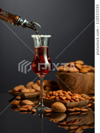 Liqueur Amaretto is poured into a glass. 110553593