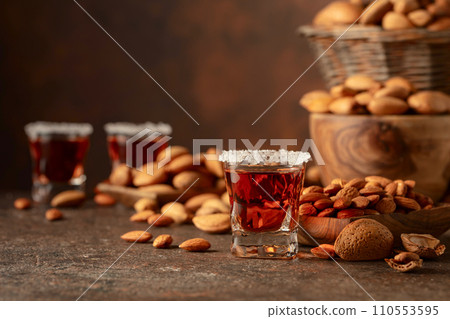 Italian liqueur Amaretto with almonds nuts on a brown background. Italian liqueur Amaretto with almonds nuts on a brown background. 110553595