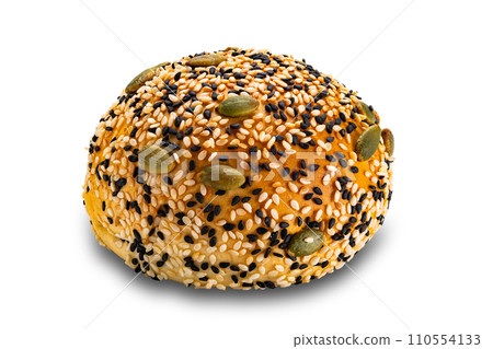 Side view of homemade burger bun sprinkled with white and black sesame and pumpkin seeds. 110554133