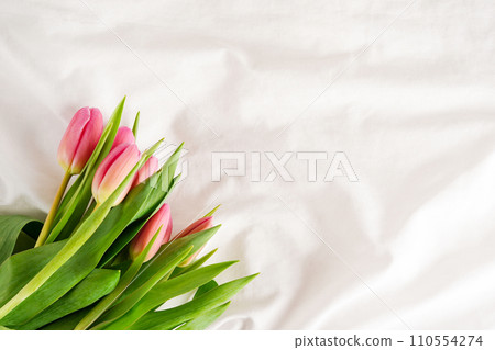 Bouquet of spring pink tulips on the messy bed, top view, copy space 110554274