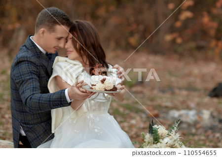 bride and groom on the nature in autumn . wedding couple with cake outdoor 110554655