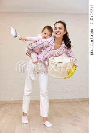 happy mother housewife is holding cute baby girl and basket with laundry , Happy family 110554753