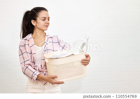 Woman is holding laundry basket with white clothes, copy space, housekeeping Woman is holding laundry basket with white clothes, copy space, housekeeping 110554769