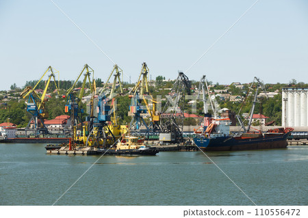 Cargo ship docked at industrial port with cranes. Freight vessel loading, maritime harbor logistics. Bulk carrier import export, commercial dock facilities. Sea transport, goods distribution. Cargo ship docked at industrial port with cranes. Freight vessel loading, maritime harbor logistics. Bulk carrier import export, commercial dock facilities. Sea transport, goods distribution. 110556472