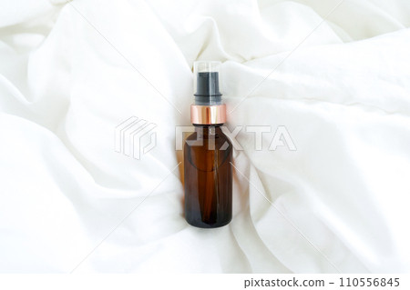 Cosmetic amber glass bottle with essential oil on white bed background. Beauty blogging Cosmetic amber glass bottle with essential oil on white bed background. Beauty blogging 110556845