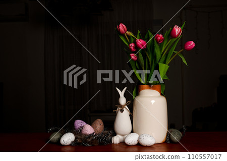 A bouquet of tulips, Easter bunny and eggs on wooden table on Scandinavian-style kitchen. Easter night 110557017