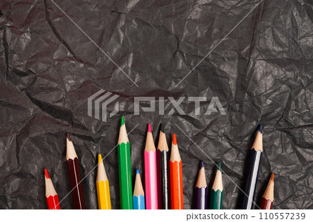 Various colored wooden pencils on black carbon paper background Various colored wooden pencils on black carbon paper background 110557239