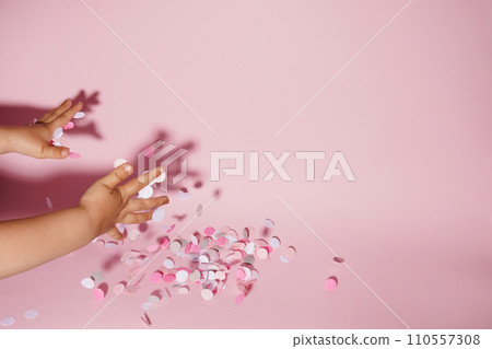 Falling confetti in child hands on bright pink background, copy space Falling confetti in child hands on bright pink background, copy space 110557308
