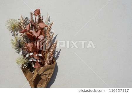 A bouquet of dried flowers in craft paper on a white background with copy space 110557317