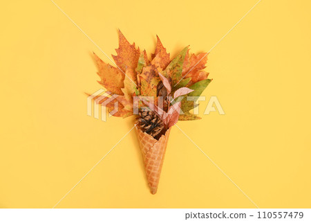 Ice cream cone with autumn leaves on light background, copy space, flat lay. Colorful bright creative layout 110557479