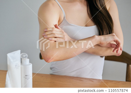 A woman in her 30s applying cream to her upper arms to take care of her body 110557874