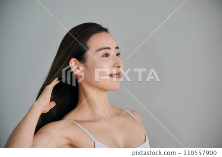 A woman in her 30s with long hair combing her hair 110557900