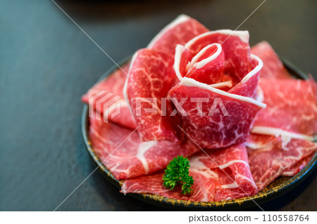 Sliced wagyu marbled beef for yakiniku on plate on black background, 110558764